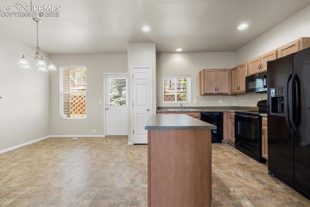 2740 Stonecrop Ridge Grove Colorado Springs, CO 80910 - Photo 12 of 42 Kitchen featuring black appliances, a center island, decorative light fixtures, a chandelier, and recessed lighting