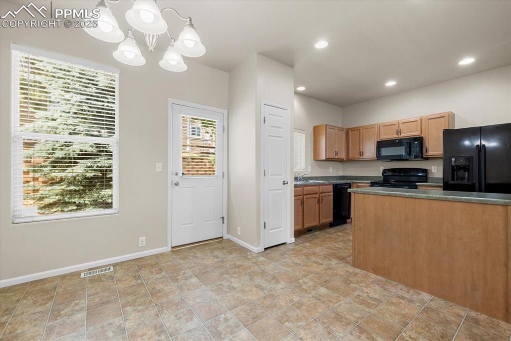 2740 Stonecrop Ridge Grove Colorado Springs, CO 80910 - Photo 13 of 42 Kitchen featuring dark countertops, black appliances, decorative light fixtures, recessed lighting, and a chandelier