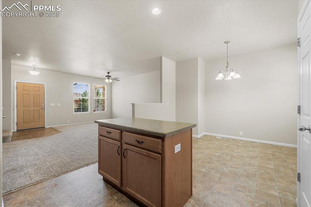 2740 Stonecrop Ridge Grove Colorado Springs, CO 80910 - Photo 15 of 42 Kitchen with open floor plan, dark countertops, pendant lighting, a center island, and a ceiling fan