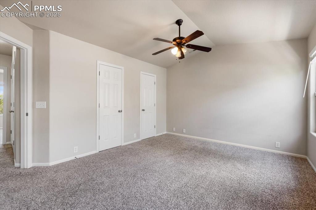2740 Stonecrop Ridge Grove Colorado Springs, CO 80910 - Photo 30 of 42 Unfurnished bedroom featuring lofted ceiling, two closets, carpet, and ceiling fan