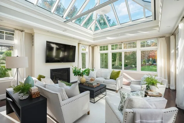 a living room with furniture large windows a fireplace and a flat screen tv