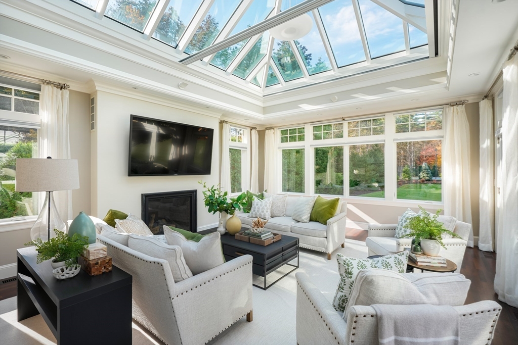 210 Monument Farm Road Concord, MA 01742 - Photo 6 of 42 a living room with furniture large windows a fireplace and a flat screen tv