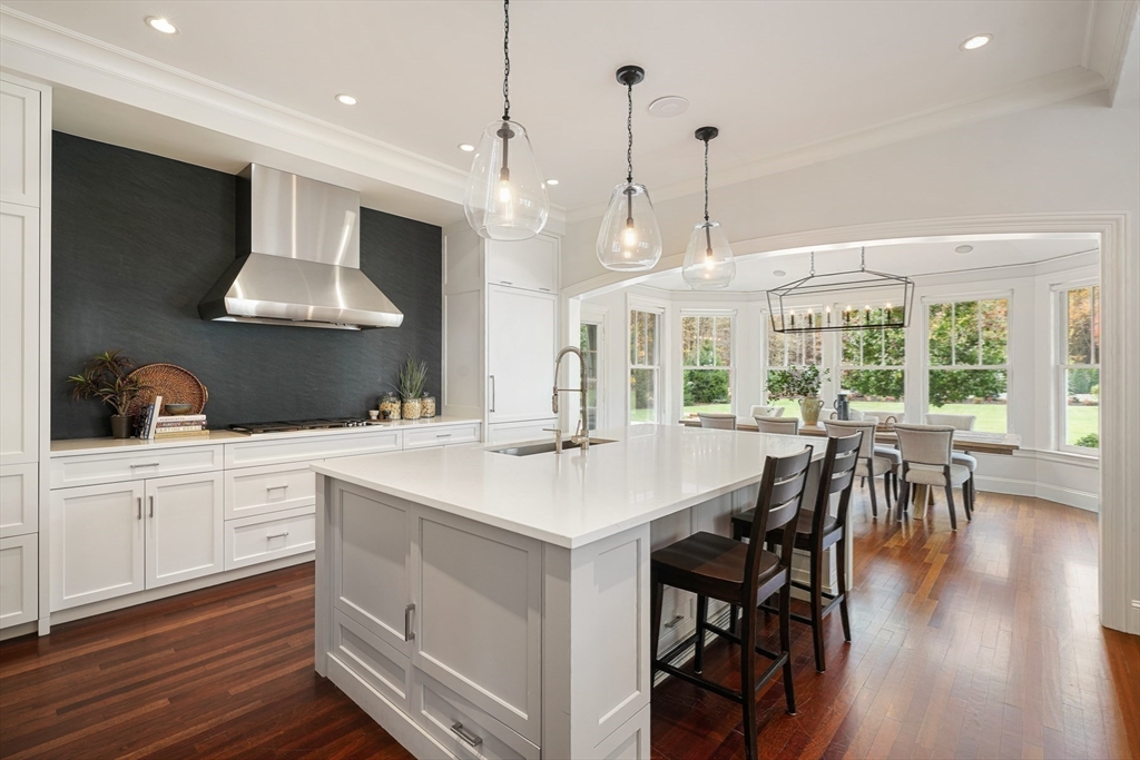 210 Monument Farm Road Concord, MA 01742 - Photo 9 of 42 a kitchen with stainless steel appliances granite countertop a stove a refrigerator a kitchen island a dining table and chairs with wooden floor
