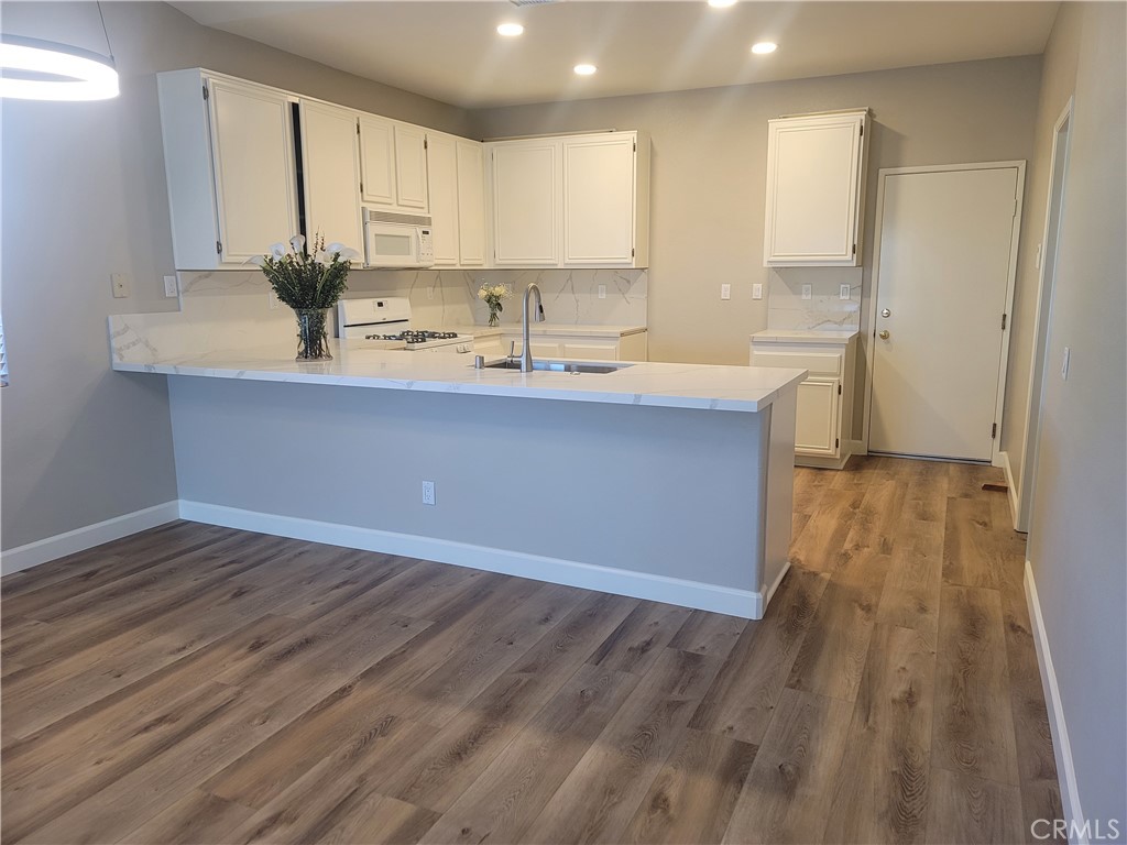 44915 Machon Road Temecula, CA 92592 - Photo 3 of 40 a kitchen with wooden floors white cabinets and sink