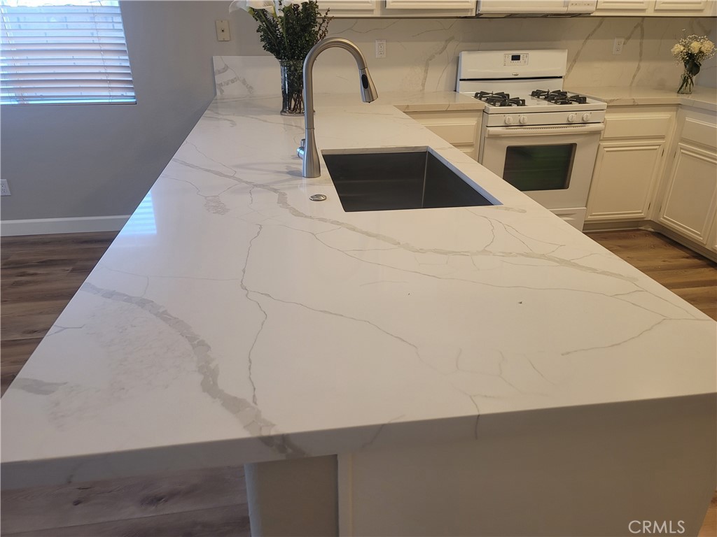 44915 Machon Road Temecula, CA 92592 - Photo 35 of 40 a kitchen with stainless steel appliances a sink a stove and white cabinets