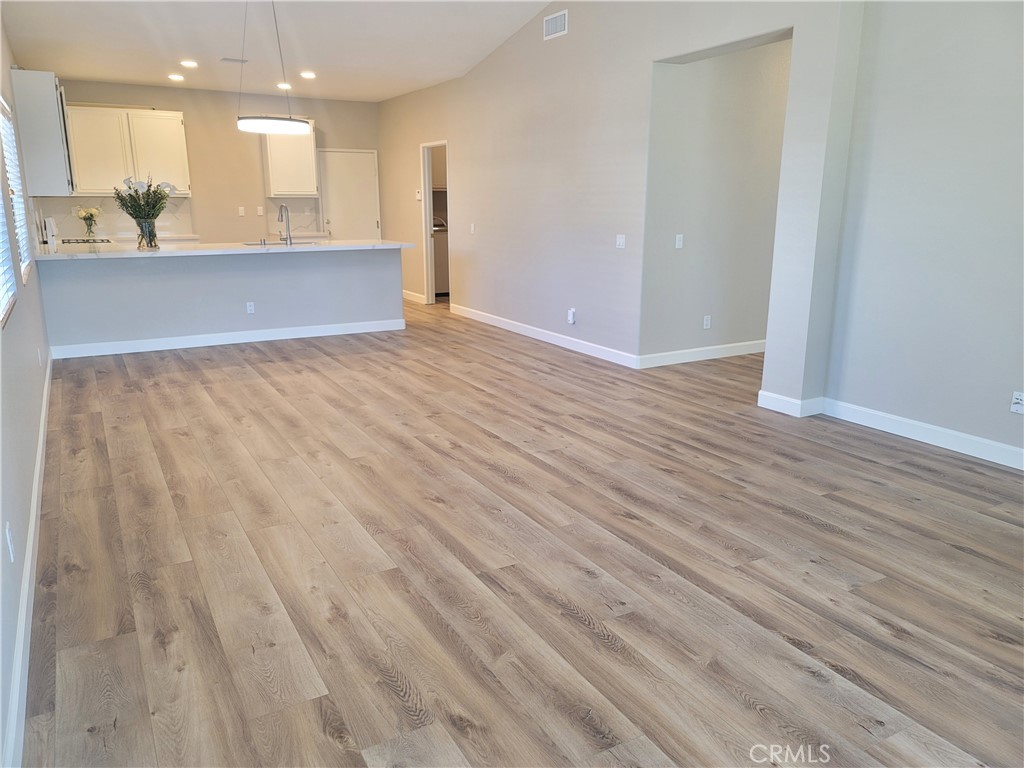 44915 Machon Road Temecula, CA 92592 - Photo 4 of 40 an empty room with wooden floor and kitchen view