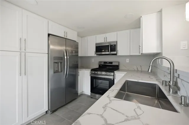 a kitchen with stainless steel appliances kitchen island a refrigerator sink and white cabinets