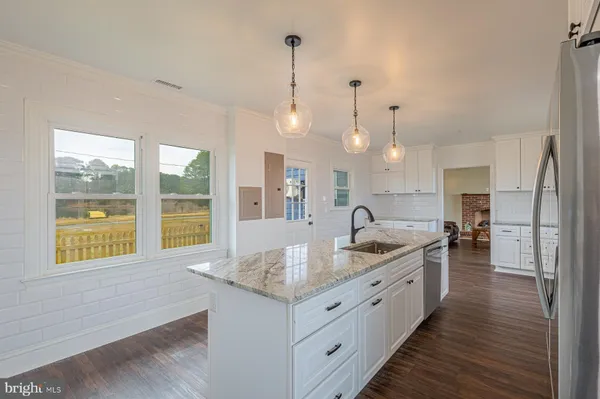 a large kitchen with kitchen island a large counter space a sink appliances and a large window