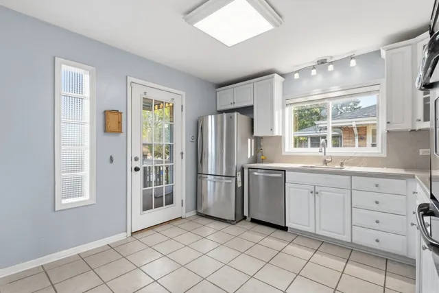 a kitchen with white cabinets and window