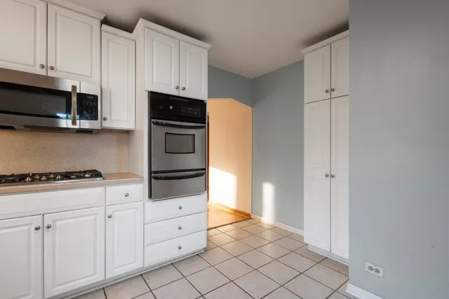 a kitchen with white cabinets and appliances