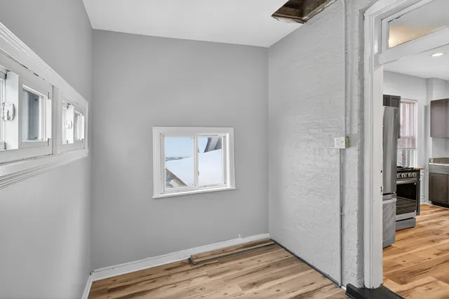 a view of an empty room with wooden floor and a bedroom