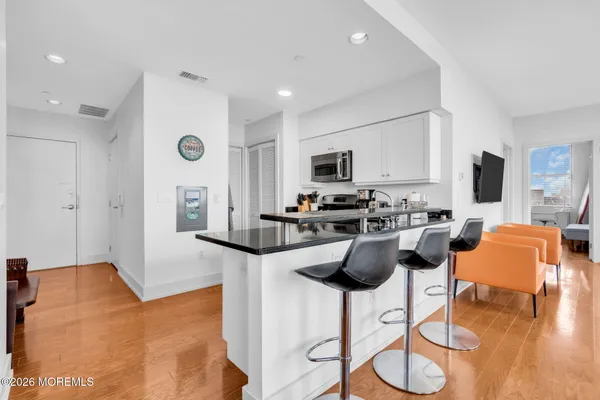 a kitchen with stainless steel appliances kitchen island granite countertop a stove a sink a refrigerator a stove a dining table and chairs with wooden floor