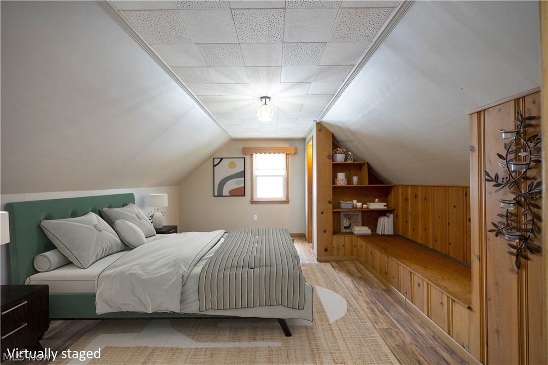 14474 Pease Road Maple Heights, OH 44137 - Photo 37 of 50 Bedroom featuring vaulted ceiling, wood walls, and light hardwood / wood-style flooring