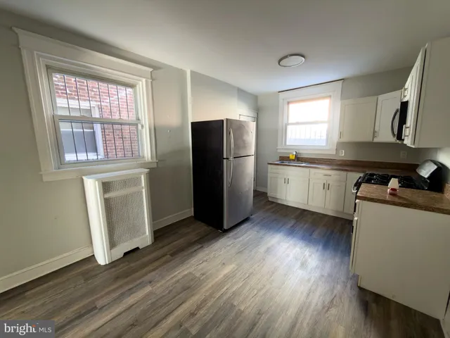 a kitchen with stainless steel appliances granite countertop a refrigerator a sink dishwasher a stove and white countertops with wooden floor