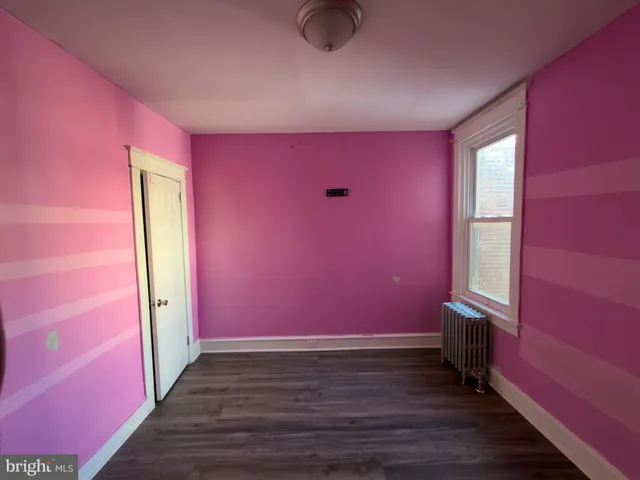 a view of an empty room with wooden floor and windows