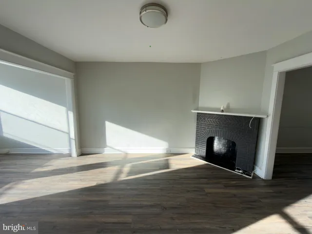 a view of empty room with wooden floor and fireplace