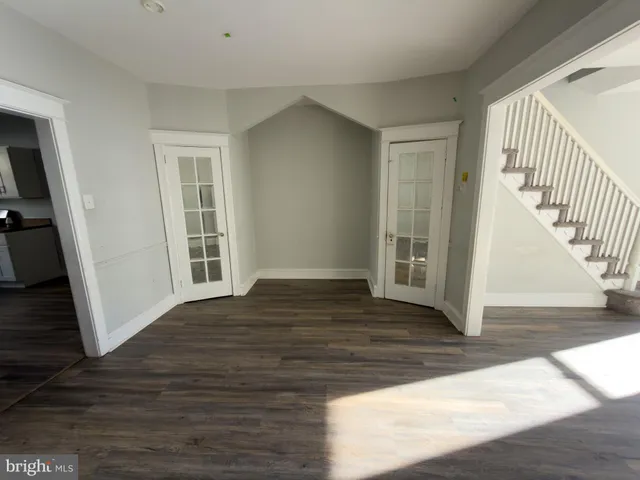 a view of an empty room with wooden floor and stairs