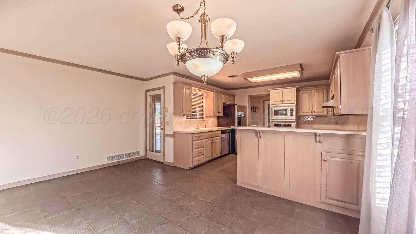 4311 Arp Place Amarillo, TX 79109 - Photo 7 of 36 a kitchen with white cabinets and chandelier