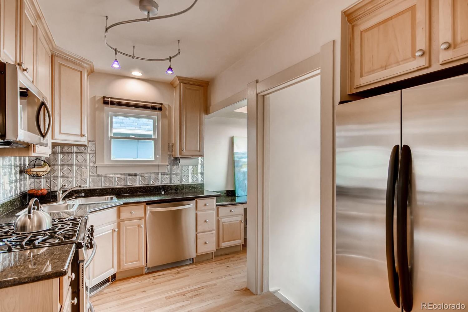 777 South Sherman Street Denver, CO 80209 - Photo 11 of 35 a kitchen with stainless steel appliances granite countertop a refrigerator a sink dishwasher a stove and white cabinets with wooden floor