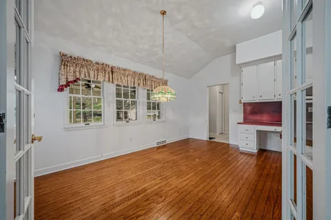 a view of a room with wooden floor a ceiling fan and a window