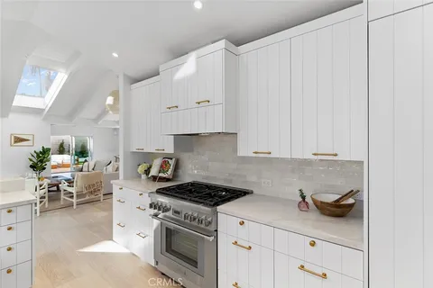 a kitchen with stainless steel appliances granite countertop a stove a sink and white cabinets