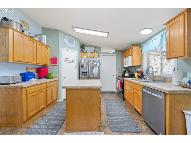 a large kitchen with stainless steel appliances kitchen island granite countertop a sink dishwasher stove and wooden cabinets
