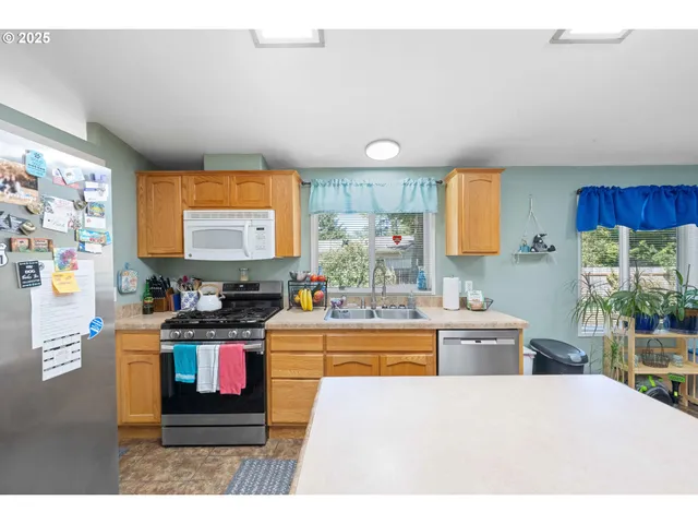 a kitchen with stainless steel appliances kitchen island granite countertop a stove a sink and a refrigerator