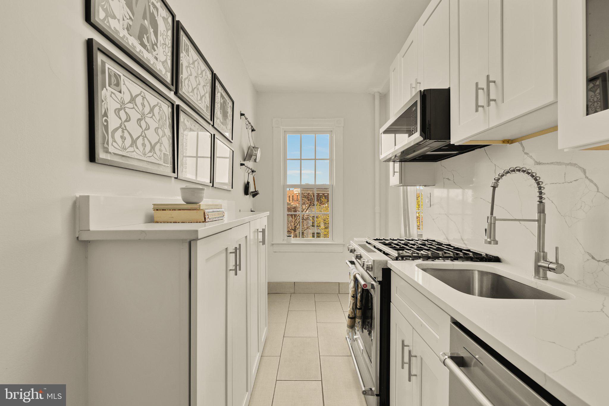 644 Massachusetts Avenue Northeast, Unit 400 Washington, DC 20002 - Photo 14 of 24 a kitchen with stainless steel appliances a sink a stove cabinets and a microwave