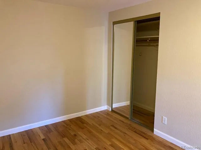 a view of an empty room with wooden floor and closet