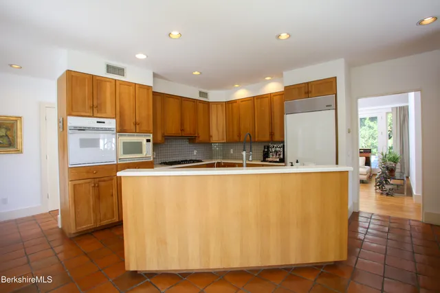 a large kitchen with stainless steel appliances a large counter top a stove a microwave a sink a refrigerator and cabinets