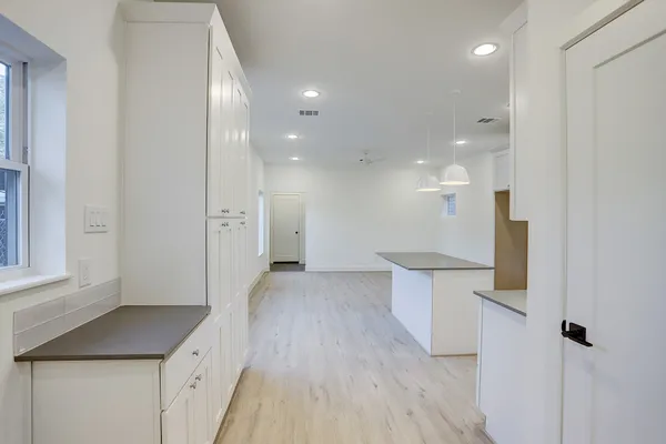 a view of a kitchen with white cabinets and wooden floor