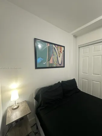 a bedroom with a bed and a lamp on dresser