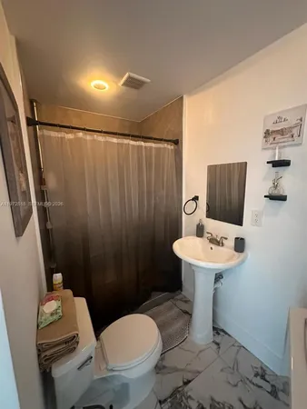 a bathroom with a sink a toilet a mirror and shower curtain