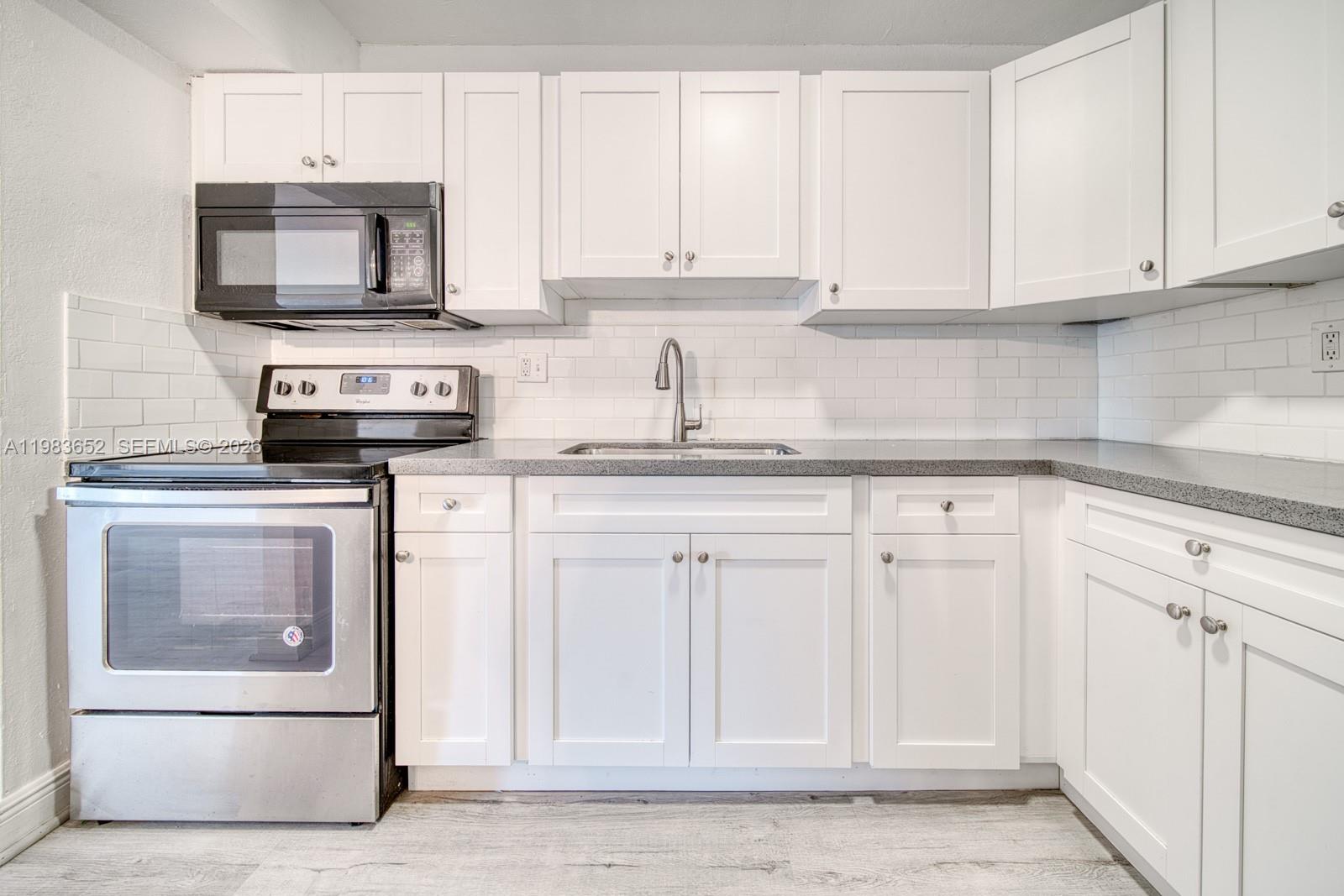 9459 Southwest 76th Street, Unit R5 Miami, FL 33173 - Photo 8 of 33 a kitchen with granite countertop white cabinets and stainless steel appliances