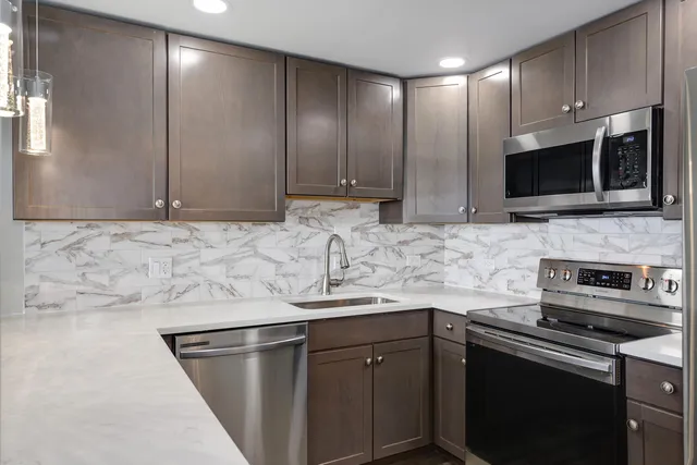 a kitchen with stainless steel appliances granite countertop a sink stove and microwave