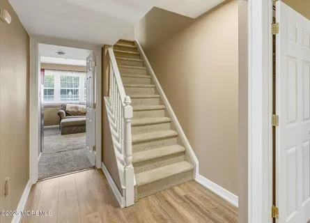 a view of a hallway to a livingroom with wooden floor and stairs