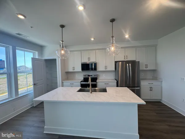 a kitchen with stainless steel appliances a dining table chairs refrigerator and microwave