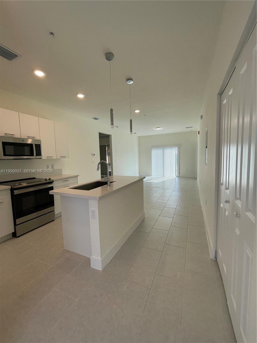8167 Northwest 41st Street, Unit E409 Doral, FL 33166 - Photo 6 of 30 a large kitchen with stainless steel appliances kitchen island granite countertop a refrigerator a sink a stove and white cabinets