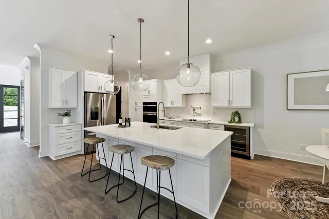 a large kitchen with kitchen island a stove a table a sink a refrigerator and cabinets