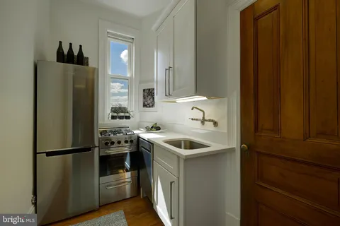 a kitchen with stainless steel appliances granite countertop a refrigerator a sink a stove and a refrigerator