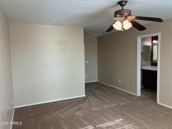an empty room with a chandelier fan and closet