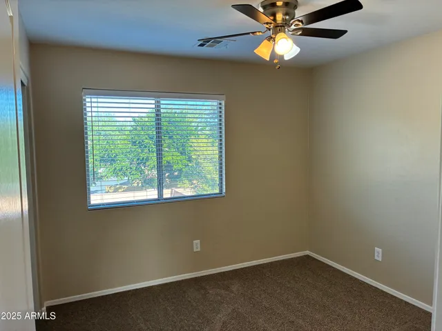 an empty room with windows and fan