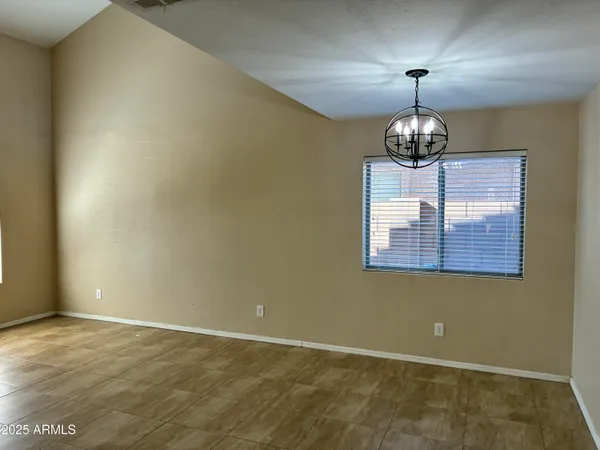 an empty room with a chandelier fan and wooden floor
