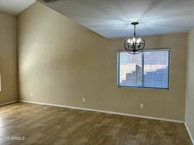 an empty room with a chandelier fan and wooden floor