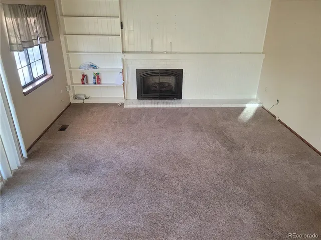 a view of an empty room with a fireplace and a window
