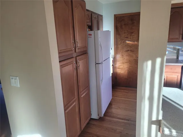 a view of a refrigerator in kitchen and an empty room