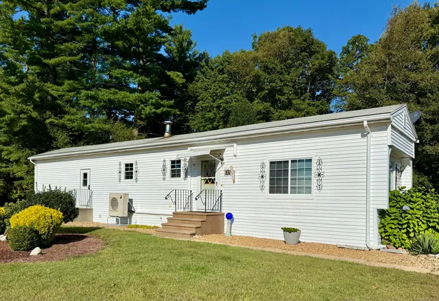 a view of a white house with a big yard and large windows