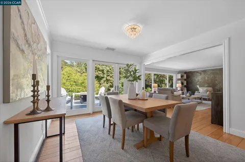 a dining room with stainless steel appliances kitchen island granite countertop a table chairs and a refrigerator