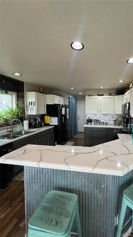 a kitchen with stainless steel appliances kitchen island granite countertop a refrigerator a stove and a sink with wooden floor