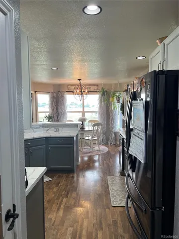 a kitchen with granite countertop a refrigerator a sink a stove and cabinets